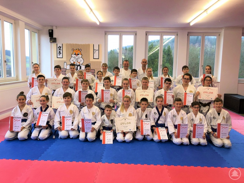 Die Kinder und Jugendlichen nach der Prüfung mit der Prüfungskommission (hinten stehend) Ramona Gruber (3. Dan), Paul Gruber (5. Dan) und Martin Lang (2. Dan) und vorne mittig kniend Romy Ritzinger (Jugendschwarzgurt, Shodan-Ho).