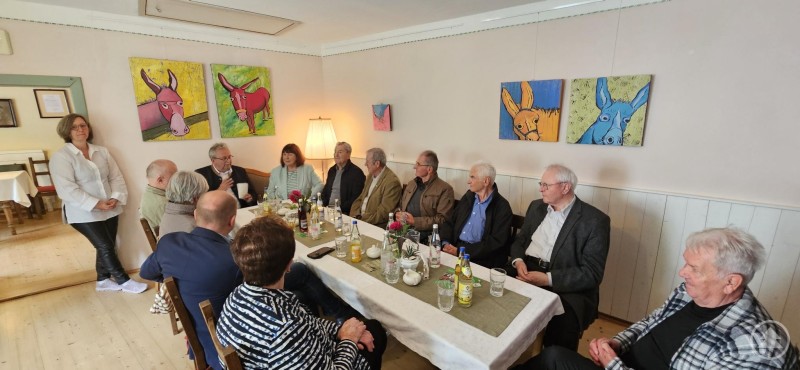 In gemütlicher Runde: Die Schlicht-Medaillenträger beim Jahrestreffen im Eiskeller Haindling. Eine Gruppe älterer Damen und Herren sitzt an einem gedeckten Tisch in einem Gastraum, im Hintergrund farbenfrohe Gemälde mit Tiermotiven an der Wand.