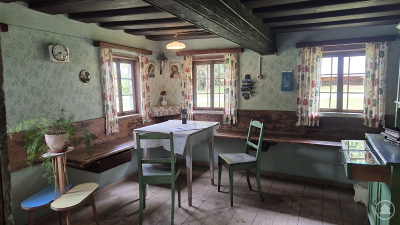 Die kleinere Stube, die durch Karolina Graf abgetrennt wurde. Stube mit alten Möbeln und Holzboden. Die Decke besteht aus alten dunklen Holzbalken.