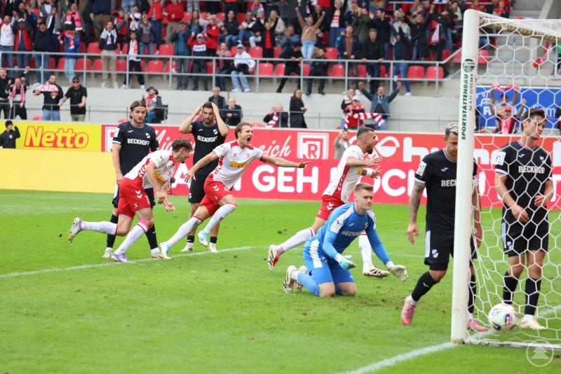 Torjubel des SSV Jahn Regensburg – Spieler rennen jubelnd davon, während der gegnerische Torwart und Verteidiger enttäuscht reagieren.