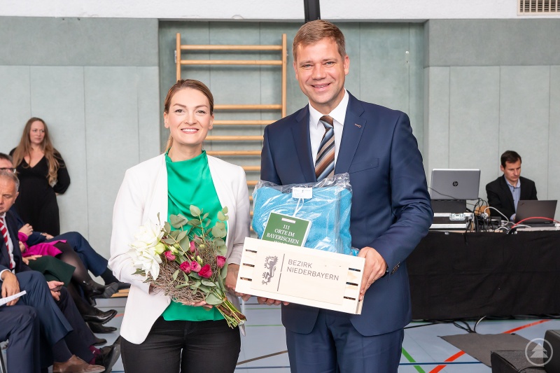 Bezirkstagspräsident Dr. Olaf Heinrich übergibt Staatsministerin Judith Gerlach Blumen und einen Geschenkkorb des Bezirks Niederbayern.