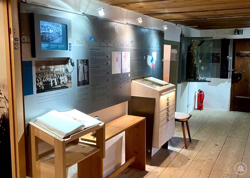 Museumsraum mit Holzdecke, interaktiven Infotafeln, Monitoren und Exponaten.