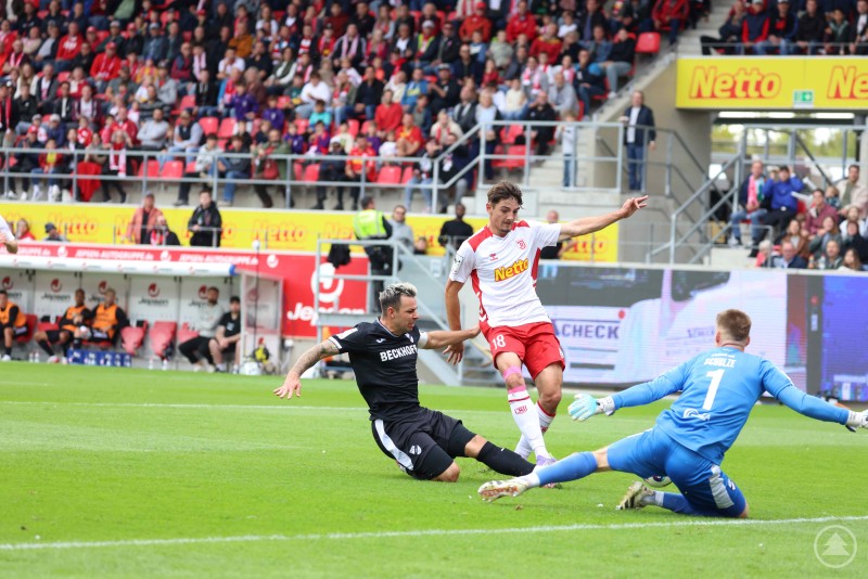 Spielsituation im Strafraum: Ein Spieler des SSV Jahn versucht, am Verteidiger und Torwart von Verl vorbeizukommen.