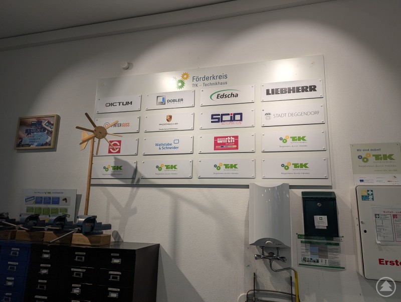 Wand mit Plastikschildern der regionalen Unternehmen, die Mitglieder im TfK-Förderkreis sind