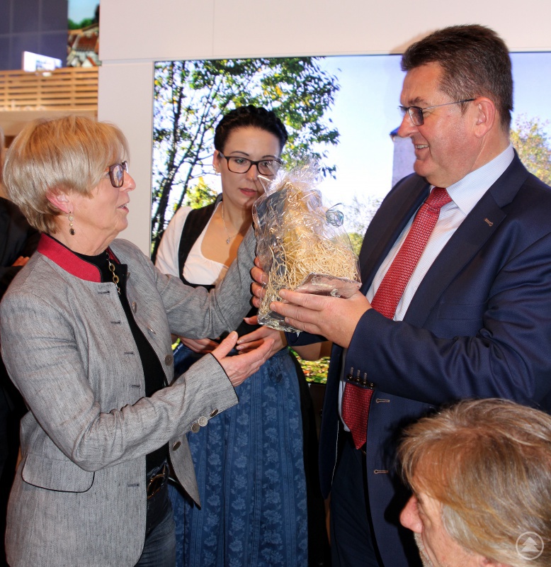 Landrätin Rita Röhrl bei der Übergabe eines Geschenkes an Franz Josef Pschierer, dem Staatssekretär im bayerischen Wirtschaftsministerium. Im Hintergrund ist Veronika Neumaier von der Arberland REGio GmbH zu sehen.