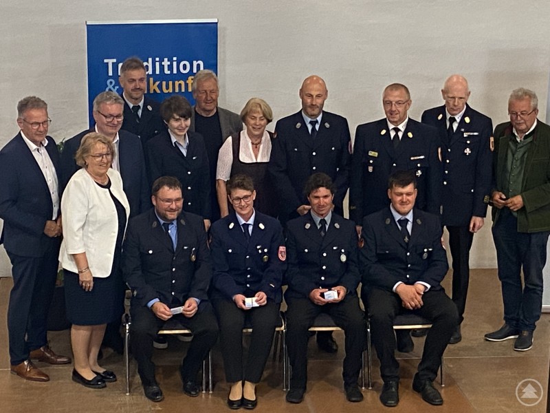Die neuen Empfänger der Ehrenamtskarte aus der Gemeinde Laberweinting gemeinsam mit den Ehrengästen um Landrat Josef Laumer (ganz rechts). Eine Gruppe von Feuerwehrleuten und Ehrengästen steht und sitzt gemeinsam für ein Gruppenfoto. Im Hintergrund ein Banner mit der Aufschrift „Tradition & Zukunft“. Einige Personen halten Ehrenamtskarten in der Hand.