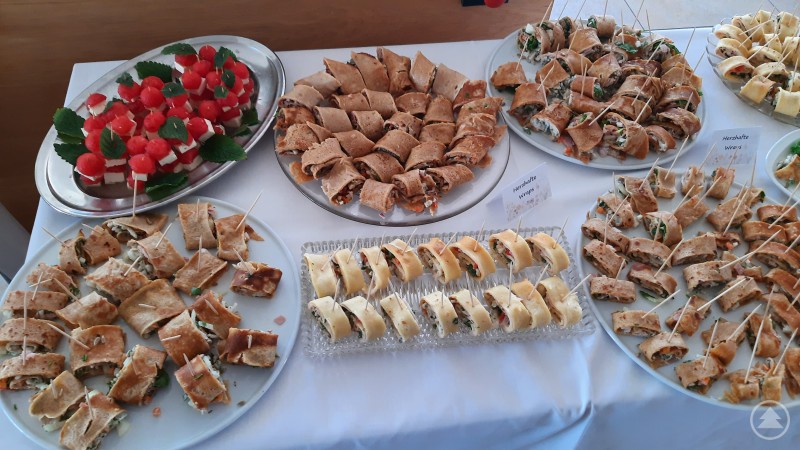 Fingerfood in vielen Variationen – Zum Abschluss ließen sich die großen und kleinen Gäste ihr selbst zubereitetes Buffet schmecken. Verschiedene Sorten Fingerfood sind appetitlich auf Tellern angerichtet, darunter Wraps, Röllchen und Obstspieße.