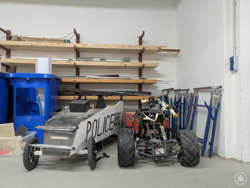 Zwei Seifenkisten stehen vor Regalen mit Holzbrettern