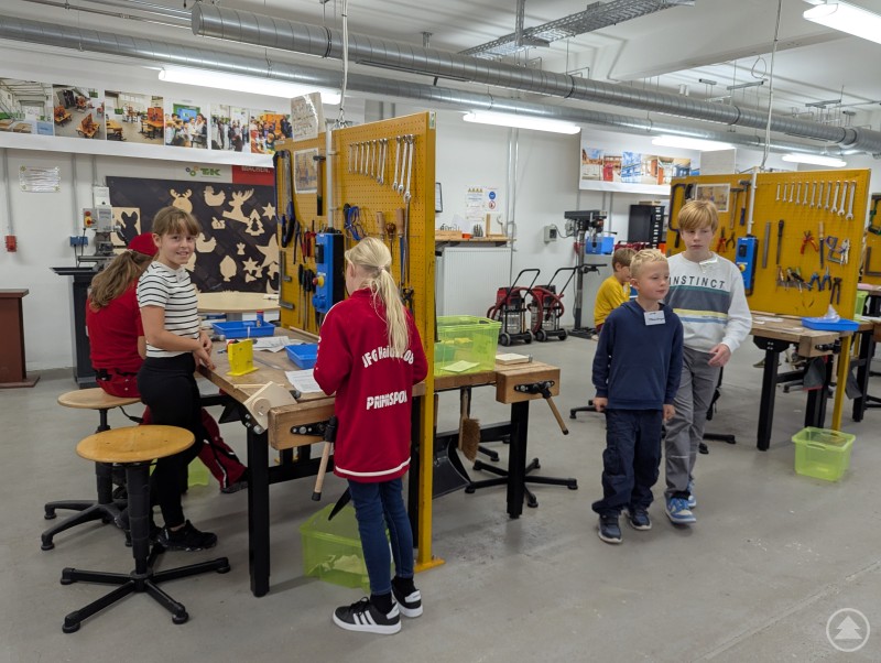 Kinder und Jugendliche von acht bis 17 Jahren begeistern sich beim TfK gemeinsam für Technik und das Handwerk. Fünf Kinder arbeiten an Holzwerkbänken an ihren Bauprojekten