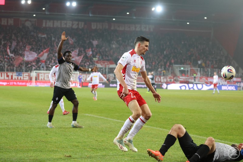 Ein Regensburger Spieler &uuml;berspringt einen am Boden liegenden Gegenspieler, der Ball ist bereits weitergespielt.