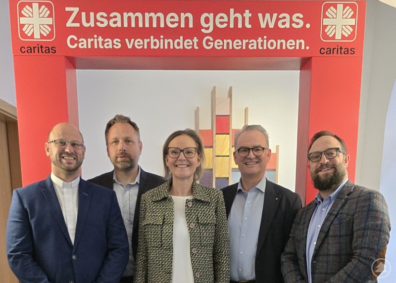 v. l.: Stanislav Brožka (Präsident, Caritas Budweis), Jiří Kohout (Caritasdirektor, Budweis), Andrea Anderlik (Vorständin, Caritasverband für die Diözese Passau e. V.), Stefan Seiderer (Vorstand, Caritasverband für die Diözese Passau e. V.) und Stefan Pimmingstorfer (Caritasdirektor, Oberösterreich) Fünf Personen stehen vor einem roten Caritas-Aufsteller und blicken in die Kamera.