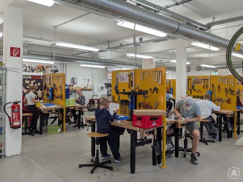 Kinder und Jugendliche sitzen und arbeiten konzentriert an den Holzwerkbänken