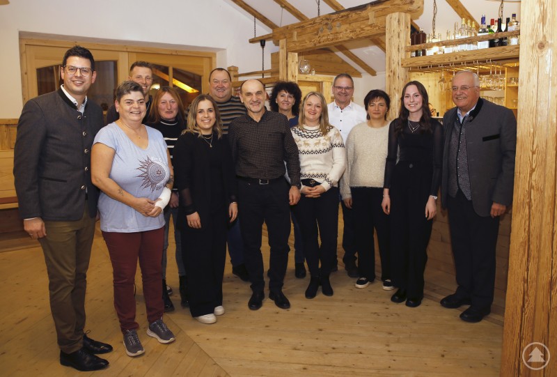 Ein mittelständischer Verwaltungsbetrieb wie Markt und VG-Verwaltung Schönberg hat auch ständig Bewegung im Team. Bürgermeister Martin Pichler dankte exemplarisch allen, die extra lange dabei waren, die kommen und gehen und sich harmonisch in die kommunale Symphonie einbringen. Eine größere Gruppe von Mitarbeiterinnen und Mitarbeitern der Marktgemeinde Schönberg steht gemeinsam mit Bürgermeister Martin Pichler in einem festlich dekorierten Stadl und posiert für ein Gruppenfoto.