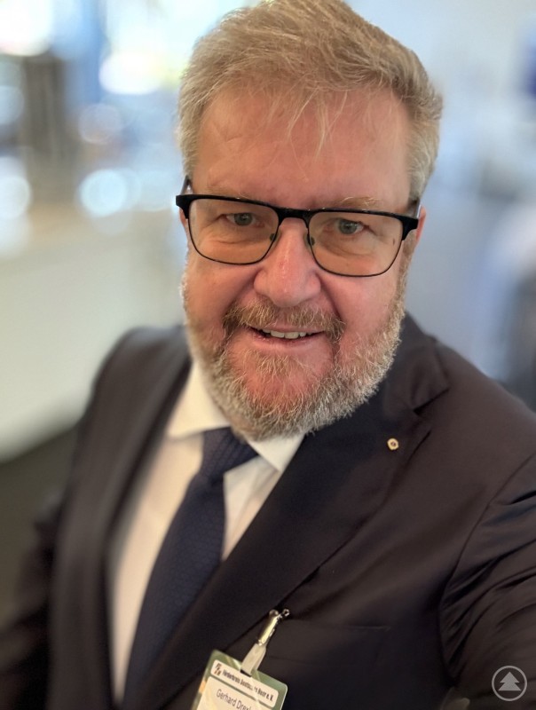 Gerhard Drexler, politischer Beirat der Bundesverbraucherhilfe e.V. Porträt eines Mannes mit Brille und grauem Bart, der einen Anzug trägt und freundlich in die Kamera blickt.