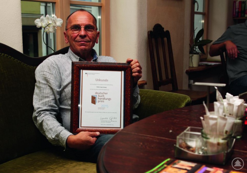 Heinz Lang mit der Urkunde des Buchhandelspreises, die ihn für sein Engagement um das Buch auszeichnet und stolz macht.
