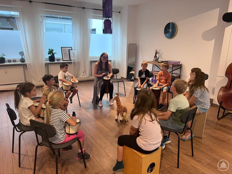 Kinder-Trommelgruppe spielen im Sitzkreis verschiedene Rhythmusinstrumente