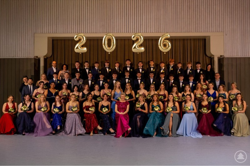 Die Abschlussklassen der Realschule Grafenau präsentierten sich beim Tanzball 2026 festlich gekleidet und stolz auf einen gelungenen Abend. Gruppenfoto der Abschlussklassen der Realschule Grafenau in festlicher Abendgarderobe. Die Absolventinnen und Absolventen sitzen und stehen in mehreren Reihen auf der Bühne, über ihnen schweben goldene Luftballons mit der Jahreszahl 2026.