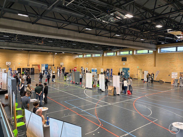 Gemeinsam stark für die Ausbildung: Vertreterinnen und Vertreter von Betrieben und Einrichtungen sowie über 100 Schülerinnen und Schüler kamen beim Azubi-Speed-Dating 2025 zusammen. Eine große Gruppe aus Jugendlichen, Lehrkräften und Unternehmensvertretern steht gemeinsam in einer Sporthalle und blickt zur Kamera. Im Hintergrund sind Messestände verschiedener Betriebe zu sehen.