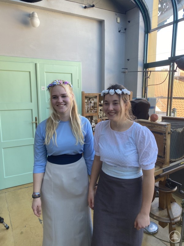 Im Atelier von Franz Seidel wurde Geschichte für die Jugendlichen unmittelbar erlebbar. Zwei Schülerinnen mit Blumenkränzen stehen in einem Raum mit historischen Requisiten und einer alten Kamera.