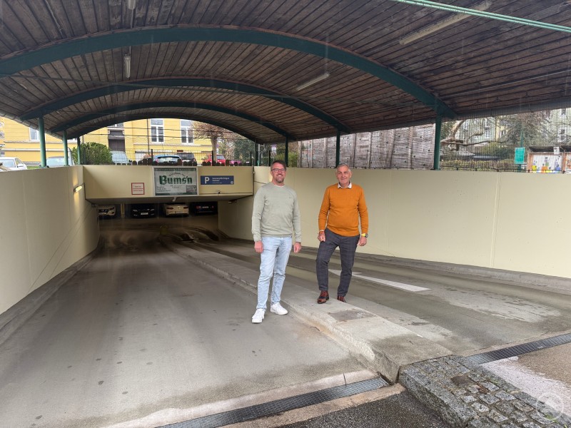 Das Parkhaus in der Tummelplatzstraße in Schärding mit neuem Parksystem. Zwei Männer stehen vor der Einfahrt eines Parkhauses, das mit einem neuen schrankenlosen System ausgestattet ist.