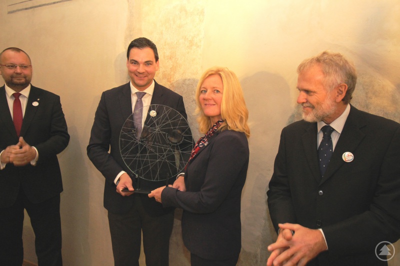 Bürgermeisterin Terezie Jenisová und Landrat Sebastian Gruber (beide Bildmitte) zusammen mit den Ehrengästen, dem stellvertretenden Vorsitzenden des Abgeordnetenhauses des Parlaments der Tschechischen Republik, Ing. Jan Bartošek (links) und dem Koordinator für Kulturprojekte im Außenministerium der Tschechischen Republik, Dr. Zdeněk Lyčka (rechts) bei der Übergabe des Gastgeschenkes