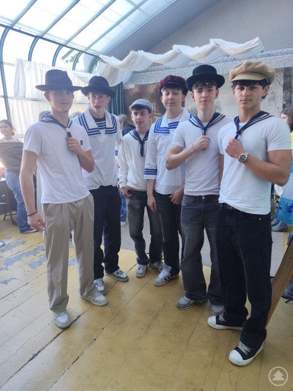 Auch die Jungen schlüpften für die Fotos in historische Kleidung und Accessoires. Eine Gruppe Schüler in Matrosenhemden und historischen Hüten steht gemeinsam im Atelier und blickt in die Kamera.