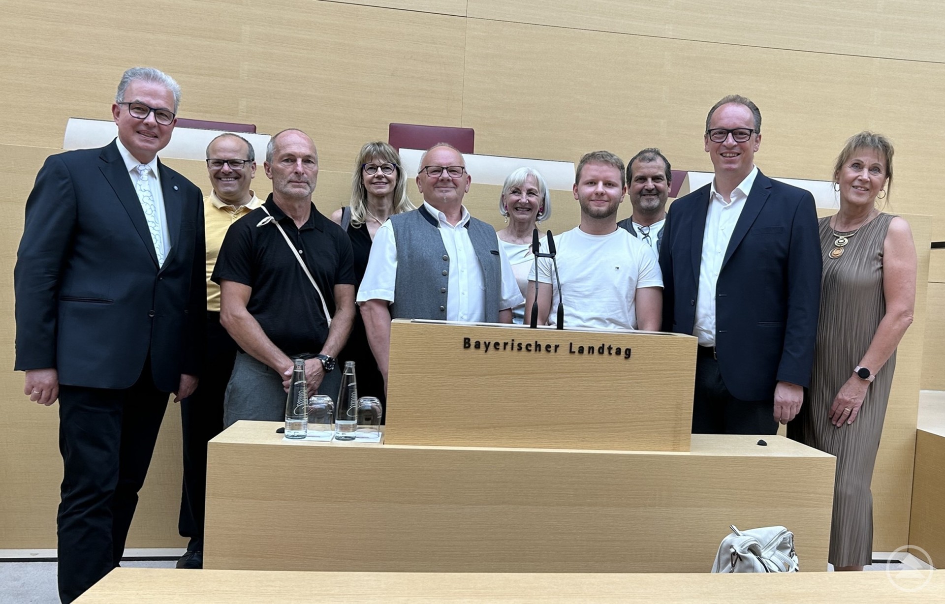 Eine Gruppe von Politikern und Gästen steht am Rednerpult des Bayerischen Landtags für ein gemeinsames Foto.