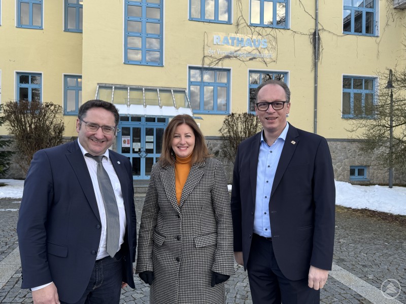 Wirtschaftsstaatssekretär Tobias Gotthardt und MdL Martin Behringer treffen Bürgermeisterkandidatin Ingrid Weiß in Zachenberg zum Austausch über Gewerbeentwicklung und Wohnraum. Drei Personen stehen vor einem gelben Gebäude mit blauen Fenstern und posieren für ein Foto, darunter Wirtschaftsstaatssekretär Tobias Gotthardt, Bürgermeisterkandidatin Ingrid Weiß und MdL Martin Behringer.