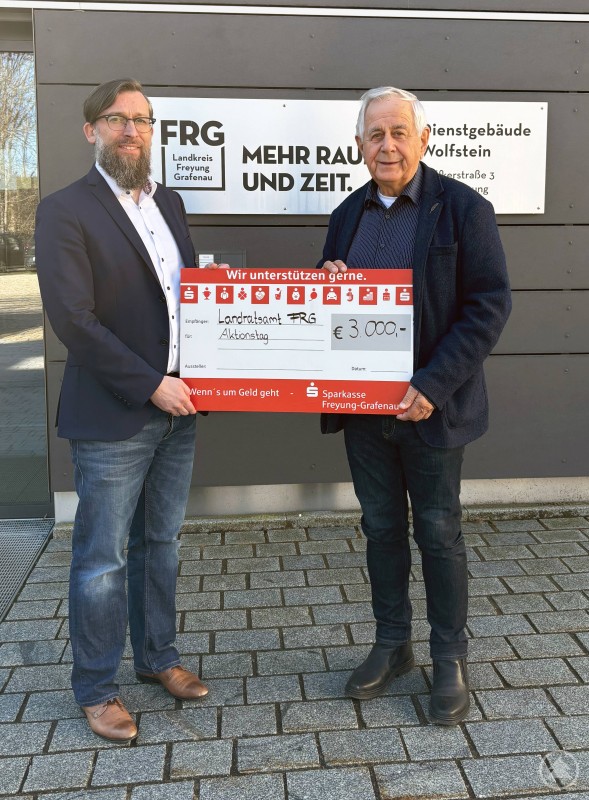 Christian Fiebig links Leiter Sachgebiet Landkreisangelegenheiten am LRA bedankte sich im Rahmen der symbolischen Scheckübergabe bei Herbert Kern sen. für seine kontinuierliche Unterstützung des Aktionstags für Menschen mit Handicap. Zwei Männer stehen vor dem Dienstgebäude Wolfstein des Landratsamtes Freyung-Grafenau und halten gemeinsam einen symbolischen Spendenscheck über 3000 Euro in den Händen.
