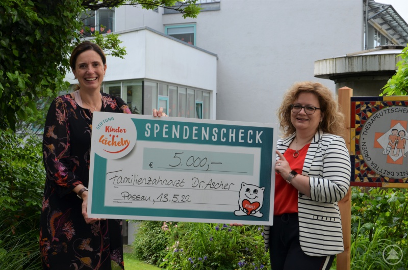Dankend nimmt Dr Maria Diekmann (l.), Vorstandsvorsitzende der Stiftung Kinderlächeln, den Scheck über 5.000 Euro von Dr. Agathe Ascher, Zahnärztin und Inhaberin der Familienzahnarztpraxis Freyung, entgegen.