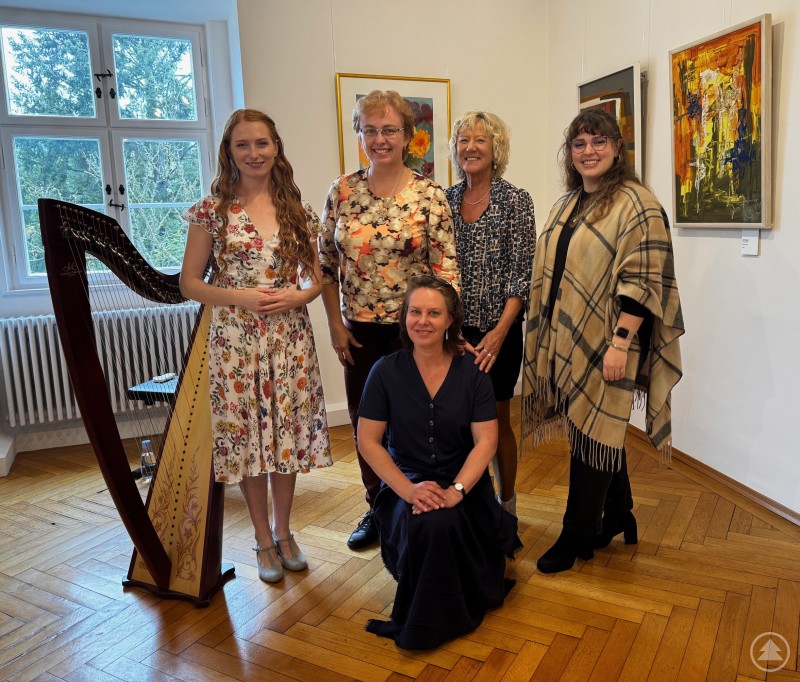 Von links: „Elfenhaft“ verzauberte Jana Kazdová mit Harfe und Gesang die Besucher in der Galerie Wolfstein. Über die erfolgreichen Freundschaftskonzerte freuten sich Stanislava Tůmová, Bürgermeisterin von Čkyně, Hana Dědová von der Synagoge Čkyně, die stellvertretende Landrätin Hilde Greiner und Kulturreferentin Gabriela Rauscher. Fünf Frauen, darunter eine Harfenistin, stehen und sitzen in einer Galerie vor bunten Gemälden. Eine Harfe ist prominent im Vordergrund zu sehen.