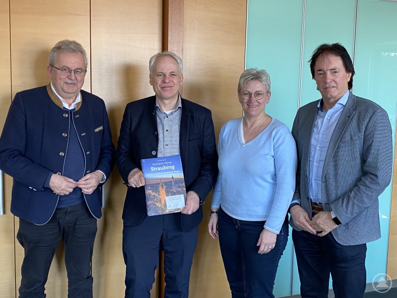 (v.l.) Landrat Josef Laumer, Ministerialbeauftragter Christian Ceglarek, Silke Raml und Heribert Ketterl beim Antrittsbesuch im Landratsamt Straubing-Bogen. Vier Personen stehen nebeneinander in einem modernen Büro oder Besprechungsraum. Zwei Männer und eine Frau tragen Anzug oder Businesskleidung, einer hält einen Bildband mit dem Titel „Straubing“. Alle blicken freundlich in die Kamera.