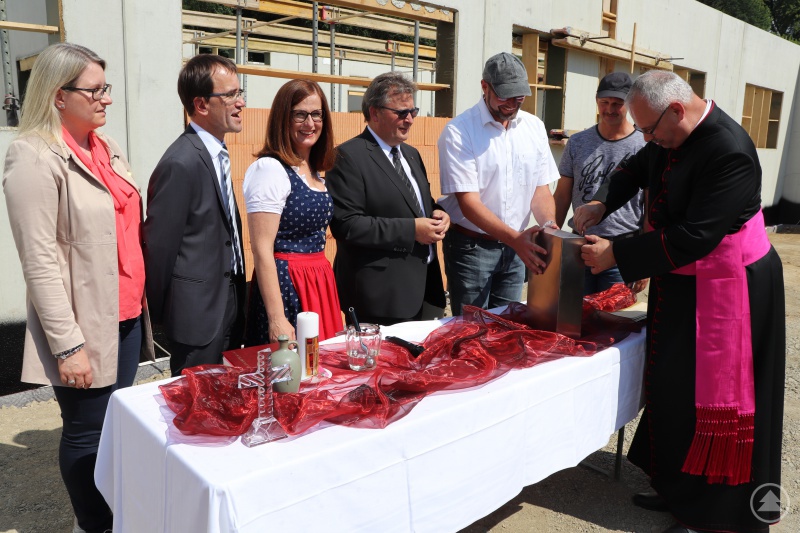 Markus Madl (Architekten-Team SSP) und Anton Feuchtinger (Schneider-Bau) (v.r.) schauten genau hin, als Generalvikar, Prälat Dr. Klaus Metzl, „Zeitbox“ verschraubte. Mit dabei: Bischöflicher Beauftragter, Diakon Konrad Niederländer, Michaela Meindl, Leiterin von St. Gisela, Caritasdirektor Michael Endres und die Abteilungsleiterin Heidi Brem.