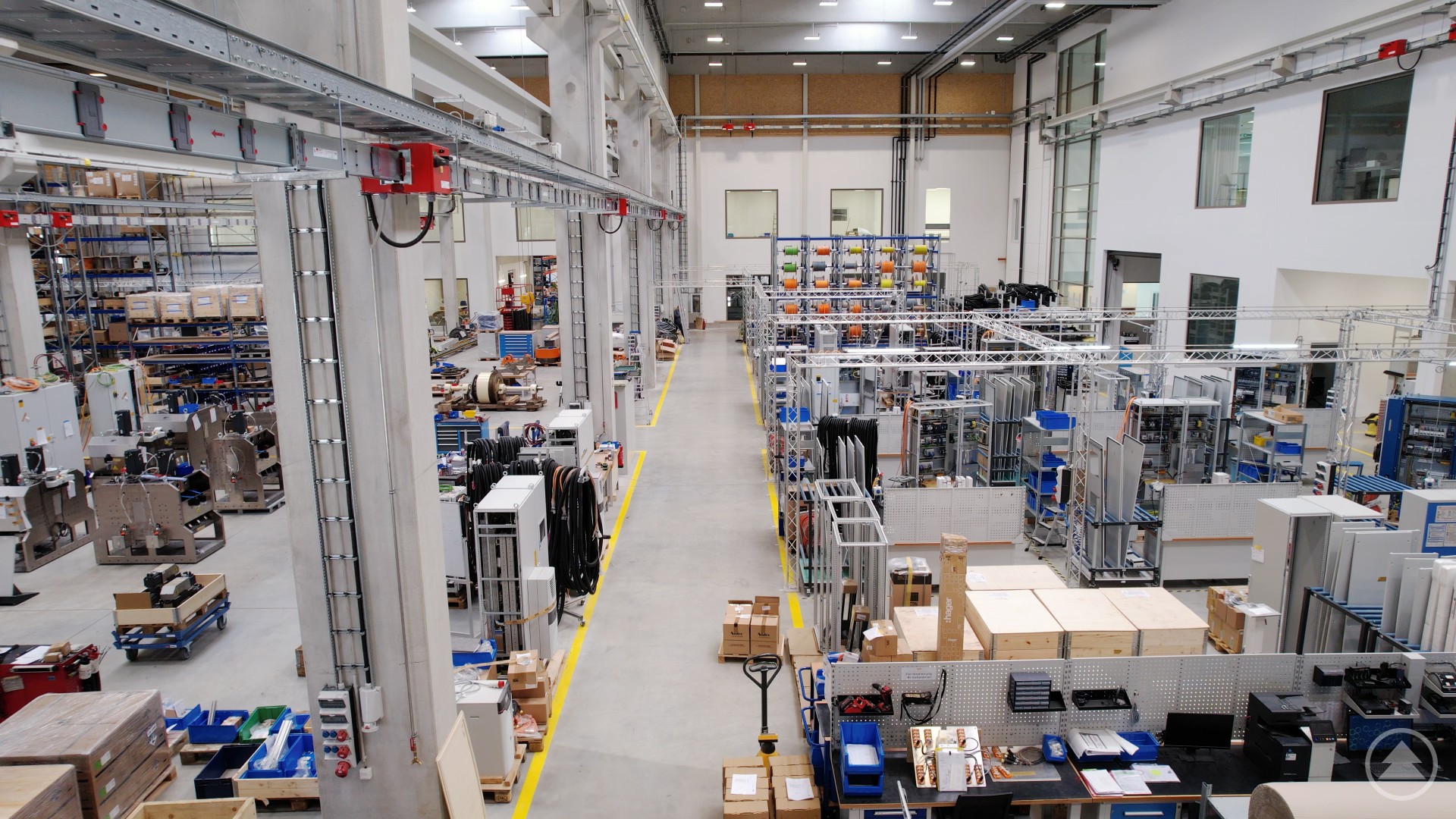 Ein Blick in die hochmoderne Produktionshalle – Herzstück des neuen Werks von Nidec SYS. Innenansicht einer weitläufigen Produktionshalle mit Maschinen, Werkbänken und Arbeitsstationen.