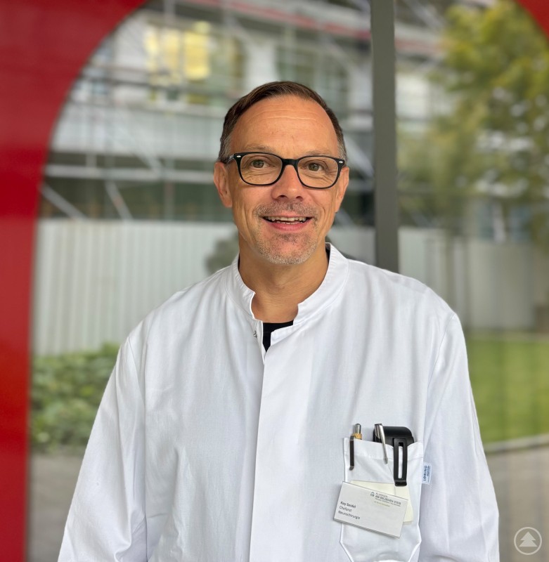 Kay Seidel, neuer Chefarzt für Neurochirurgie am Krankenhaus Freyung. Porträtfoto von Chefarzt Kay Seidel im weißen Arztkittel, freundlich in die Kamera blickend.