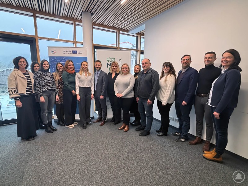 Nutzen die Möglichkeit eines partnerschaftlichen Austausches auf Verwaltungsebene: v.l. Beate Rolli-Kordick (LRA), Karin Saibold (LRA), Ramona Molz (LRA), Julia Bauer (LRA), Selma Sedova-Keck (LRA), Barbara Schober (LRA), Aleš Kolář (Třeboň), Petra Pikna Jánská (Třeboň), Hana Burešová (Třeboň), Petra Mejdrechová (Třeboň), Pavel Zajíček (Třeboň), Gabriela Rauscher (LRA), Christian Fiebig (LRA), Daniel Schachtner (Euregio) und Veronika Tůmová (Euregio). Eine größere Gruppe von Mitarbeitenden aus deutscher und tschechischer Verwaltung steht gemeinsam in einem modernen Besprechungsraum für ein Gruppenfoto nebeneinander.