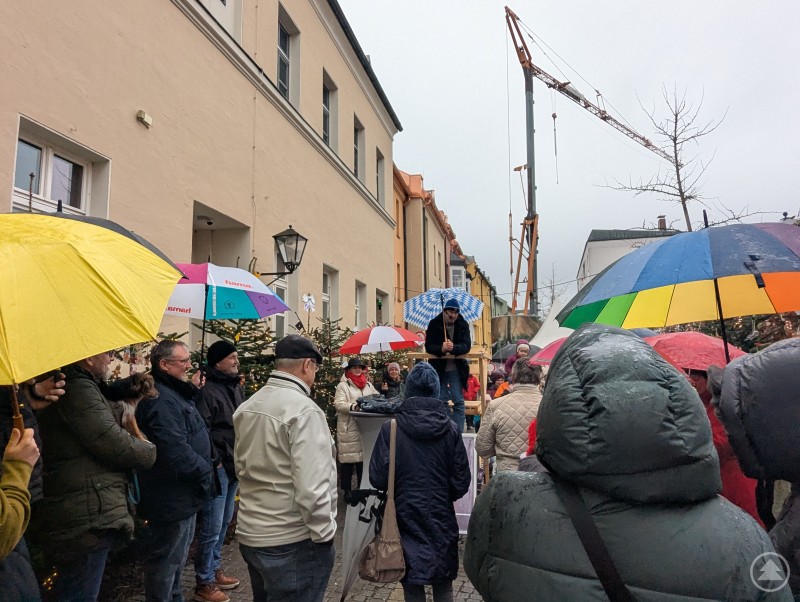 Besucher mit Regenschirmen und Winterjacken bei der Christbaumversteigerung