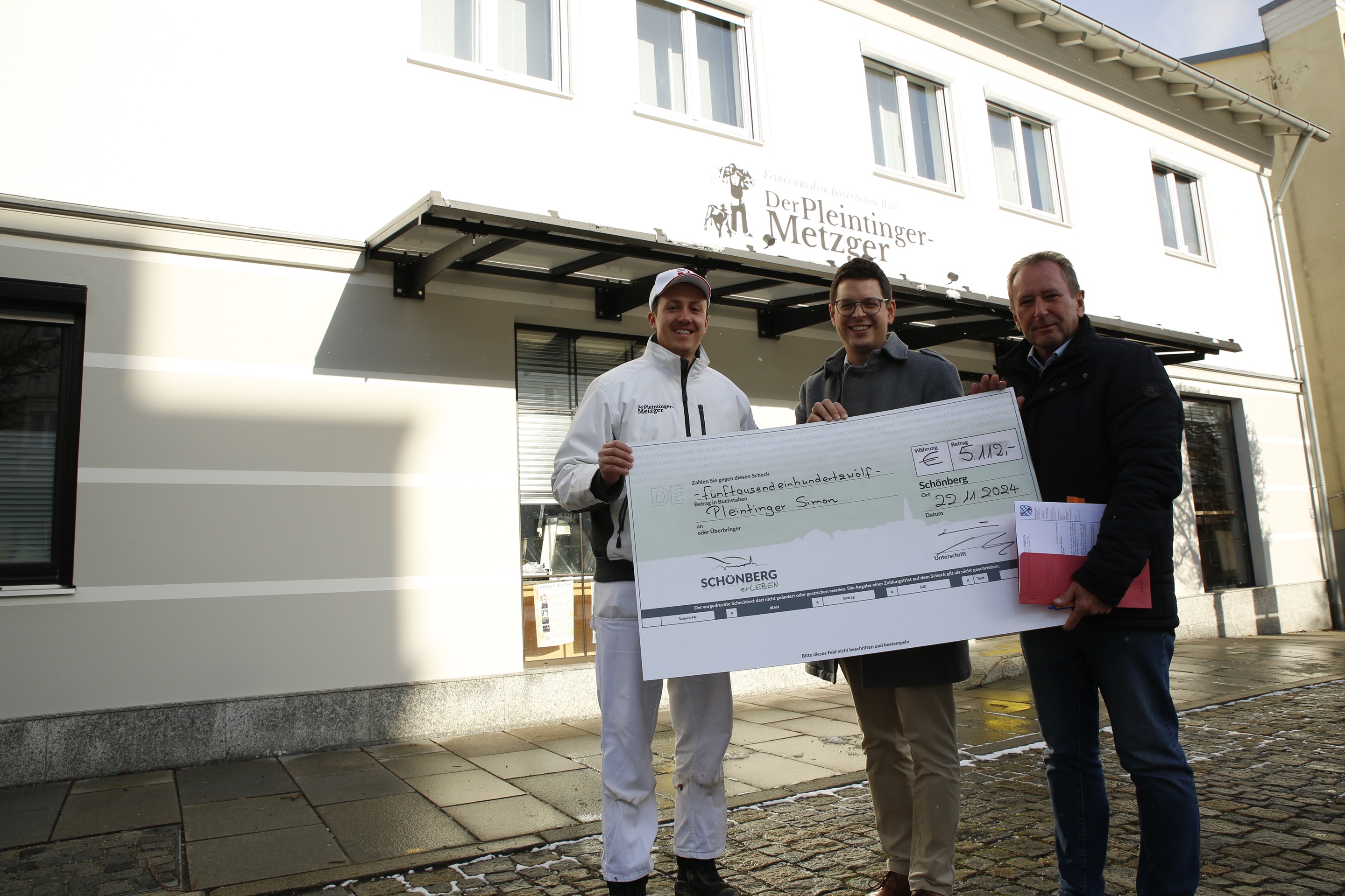 Bürgermeister Martin Pichler (m.) und Geschäftsleitender Beamter Helmut Hörtreiter (r.) überreichten an Simon Pleintinger einen Scheck dafür, dass er mit viel Geschmack den Ort attraktiv und ausgesprochen lecker erhält.