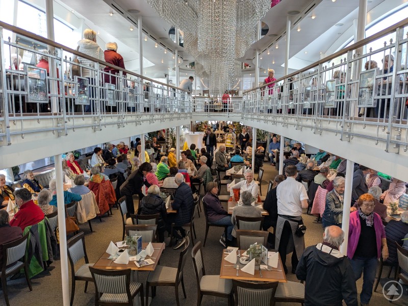 So groß war die Freude am gemeinsamen Ausflug, dass das Kristallschiff nicht ausreichte: Rund 400 Seniorinnen und Senioren gingen an Bord – auf zwei Schiffen voller guter Laune, Musik und Begegnungen. Das Bild zeigt einen gut besuchten, zweigeschossigen Veranstaltungsraum auf einem Schiff oder in einem modernen Ausflugslokal, gefüllt mit zahlreichen Seniorinnen und Senioren. An festlich gedeckten Tischen wird gegessen, geredet und gelacht, während Servicekräfte durch die Reihen gehen. Auf der Galerie im Obergeschoss schlendern weitere Gäste entlang der Reling, von der aus man nach unten blicken kann. Die Szene wirkt lebhaft und fröhlich – es handelt sich vermutlich um einen Seniorenausflug im Rahmen des Ilzer Lands 2025, bei dem Geselligkeit, Austausch und ein schöner Tag in angenehmer Atmosphäre im Mittelpunkt stehen.