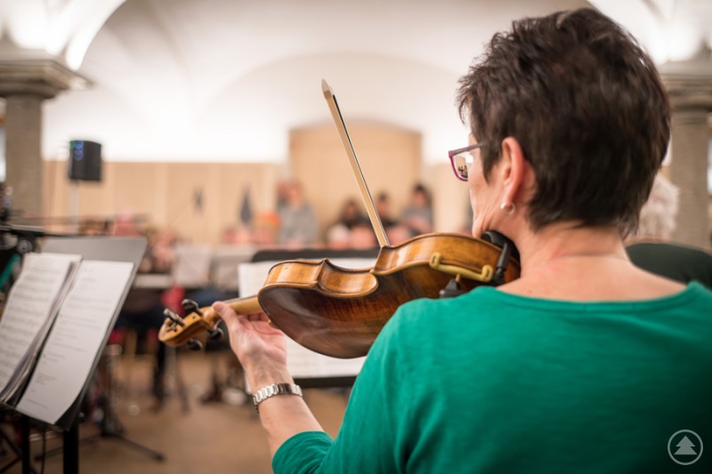 Das Ensemble „Lieblingsstück“ überzeugt mit frischer Weltmusik. Eine Frau spielt Geige vor einer verschwommenen grünen Naturkulisse.