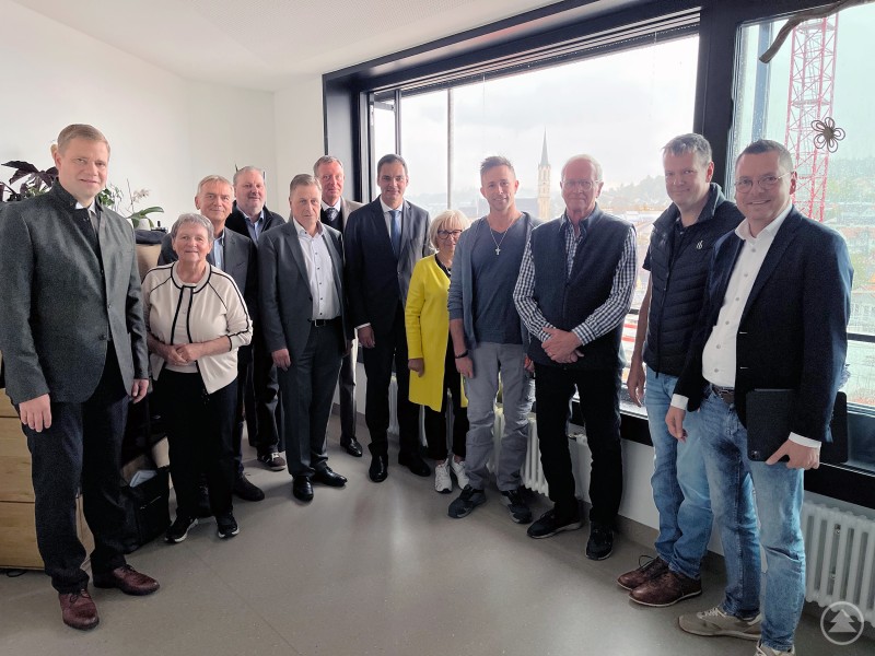 Die Aufsichtsratsmitglieder Dr. Olaf Heinrich, Renate Cerny, Prof. Dr. Horst Kunhardt, Eduard Schmid, Alexander Mayer, Geschäftsführer Marcus Plaschke, Landrat und Aufsichtsratsvorsitzender Sebastian Gruber, Helga Weinberger, Technischer Leiter Christian Siglmüller, Gunther Schlosser, Florian Habenberger und Heinz Pollak informierten sich über den Baufortschritt am Krankenhaus Freyung. Eine Gruppe von zwölf Personen steht in einem modernen Besprechungsraum mit großem Fenster, durch das man auf die Stadt Freyung und einen Baukran blickt. Die Anwesenden posieren lächelnd für das Gruppenfoto, mehrere tragen Anzüge oder Blazer.