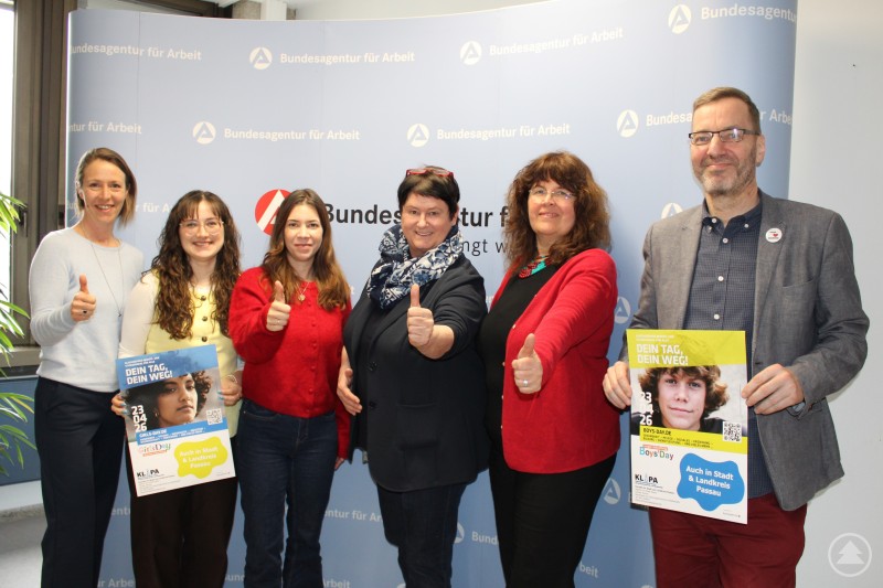 von links: Daniela Taverne Agentur für Arbeit Passau, Stefanie Mikla Handwerkskammer Niederbayern Oberpfalz, Dr Simone Zweck Universität Passau, Patrizia Hager Landratsamt Passau, Perdita Wingerter Verein Gemeinsam Leben und Lernen in Europa e.V., Thomas Kujawa Verein Gemeinsam Leben und Lernen in Europa e.V. Sechs Personen aus verschiedenen Institutionen stehen vor einer Wand der Bundesagentur für Arbeit und halten Plakate für Girls Day und Boys Day in die Kamera.