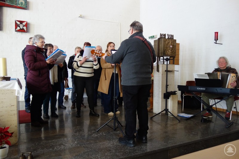 Der Lindberger Chor unter Leitung von Gerhard Stich gestaltete das erste Neujahrskonzert in der Kapelle des Caritas Seniorenheims St. Helena in Zwiesel, musikalisch begleitet von Adrian Kreuzer. Ein Chor singt in einer Kapelle vor einem Notenständer, vorne leitet ein Mann die Gruppe. Rechts sitzt ein Musiker am Keyboard, einige Zuhörer sind zu sehen.