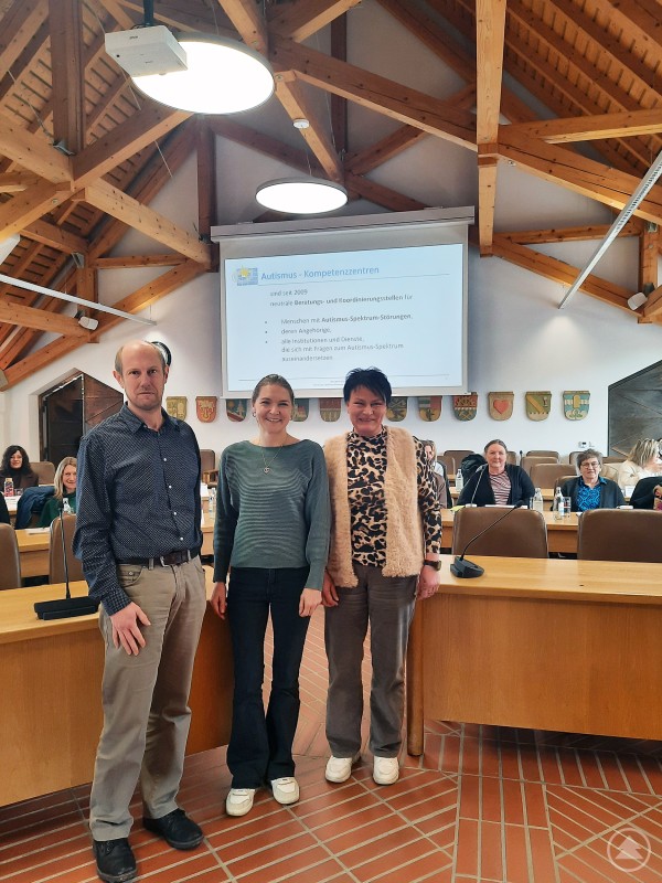v.l.: Thomas Seidl Sachgebietsleiter Amt für Kinder und Familie FRG, Monika Feilmeier von der Netzwerk Autismus Niederbayern Oberpfalz GmbH und Manuela Schwarz von der Koordinierenden Kinderschutzstelle KoKi am Landratsamt FRG Drei Personen stehen im Sitzungssaal des Landratsamtes vor einer Präsentation zum Thema Autismus, im Hintergrund sitzen weitere Teilnehmer.
