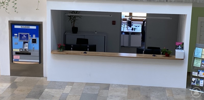Die neue Empfangstheke des Bürgerservices im Landratsamt Straubing-Bogen bietet Bürgerinnen und Bürgern eine zentrale Anlaufstelle. Blick auf die neue Empfangstheke im Landratsamt Straubing-Bogen mit Holzauflage und dahinterliegenden Arbeitsplätzen, links daneben ein Selbstbedienungsterminal.