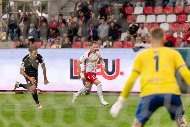 Ein Spieler des SSV Jahn läuft mit Ball am Fuß in Richtung gegnerisches Tor, ein Verteidiger und der Torwart von Rot-Weiss Essen sind in Aktion.