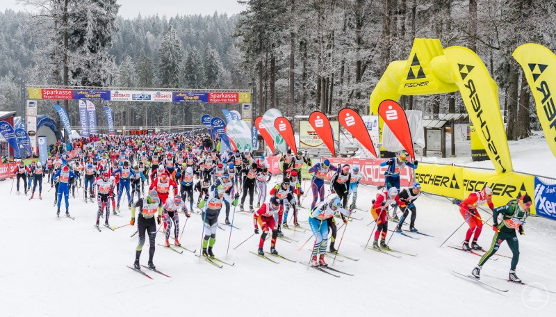 Massenstart beim Skadi Loppet am Bretterschachten: Am 24. und 25. Januar 2026 treffen sich in Bodenmais Skimarathon-Läufer aus vielen Nationen. Massenstart beim Skimarathon auf einer verschneiten Loipe, viele Langläufer stehen dicht gedrängt an der Startlinie, daneben Fahnen und Banner.