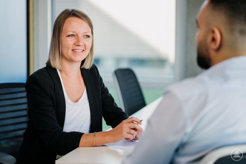 Gründungsberaterin Christina Altmann hilft Gründern über die Hürden im Gründungsprozess und zeigt ihnen den Wert einer guten Vorbereitung. Eine Frau im Business Outfit sitzt an einem Tisch und führt ein Beratungsgespräch mit einem Mann in einem modernen Büro.