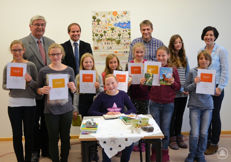 Leonie Ranzinger (sitzend) freut sich über ihren Erfolg, mit ihr auch die Klassensieger mit ihren Urkunden. Dahinter (v.r.) die strenge Jury: Verena Lohmann, die Vorjahressiegerin Sophie Ettl, Tassilo Pichlmeier und Daniel Reitmeier zusammen mit Schulleiter Günther Schwarzbauer