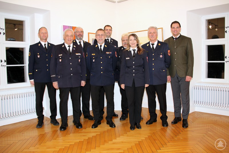 Landrat Sebastian Gruber (rechts) und KBR Martin Bauer (links) mit den verabschiedeten Mitgliedern der bisherigen Kreisbrandinspektion. Neun Mitglieder der bisherigen Kreisbrandinspektion, darunter eine Frau, stehen gemeinsam mit Landrat Sebastian Gruber und dem neuen Kreisbrandrat Martin Bauer für ein Gruppenfoto in einem hellen Raum. Mehrere tragen Feuerwehr-Uniformen und Ehrenzeichen.